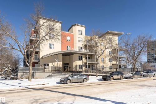 This property features a multi-story building with a light-colored facade, contrasting orange accents, and balconies - 107 10118 106 Avenue, Edmonton, AB - Outdoor