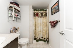 Bathroom featuring a shower with tiled walls, a toilet, and a vanity with a light-colored countertop and an integrated sink - 