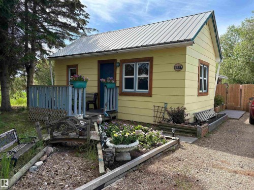 Yellow siding exterior with a metal roof and blue trim accents. - 5117 52 Avenue, Elk Point, AB - Outdoor