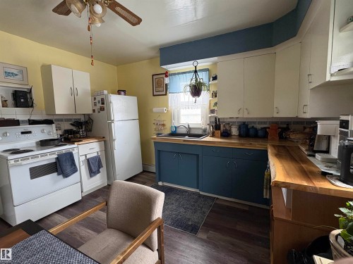 The kitchen features white upper cabinetry, blue lower cabinetry, and wood countertops - 5117 52 Avenue, Elk Point, AB - Indoor Photo Showing Kitchen