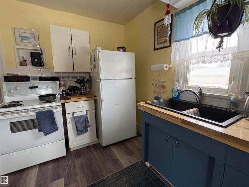 The kitchen features a white electric range, a white refrigerator, and white upper cabinetry - 5117 52 Avenue, Elk Point, AB - Indoor Photo Showing Kitchen With Double Sink
