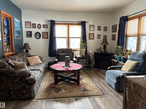 The spacious living room features wood-look flooring and multiple windows with blinds. - 5117 52 Avenue, Elk Point, AB - Indoor Photo Showing Living Room