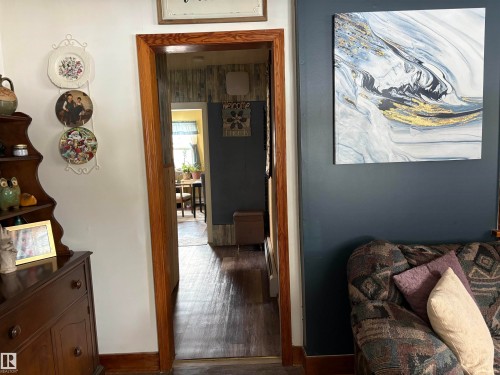 Interior view showcasing a deep blue accent wall, a wooden doorframe, and light-colored hardwood flooring - 5117 52 Avenue, Elk Point, AB - Indoor Photo Showing Other Room