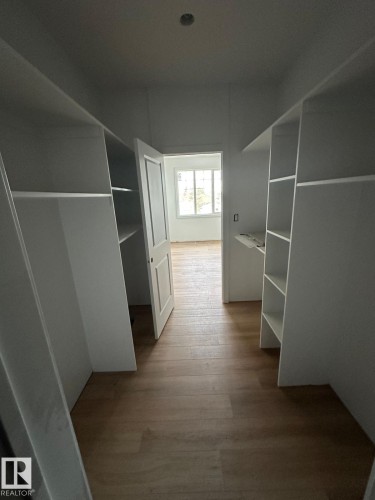 This property features a well-appointed dressing area with built-in shelving, hanging space, and light wood-style flooring - 9214 152 Street, Edmonton, AB - Indoor