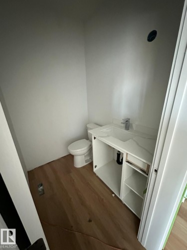 Bathroom featuring light wood-style flooring, a white vanity with an integrated sink and chrome faucet, and a white toilet - 9214 152 Street, Edmonton, AB - Indoor Photo Showing Bathroom