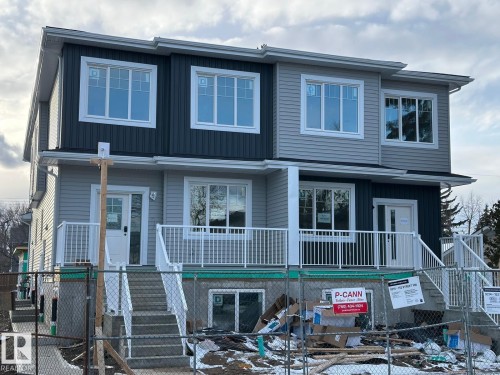 This property features a contemporary exterior with light grey and dark grey siding, white window trim, and white railings on the front porches - 9214 152 Street, Edmonton, AB - Outdoor With Facade