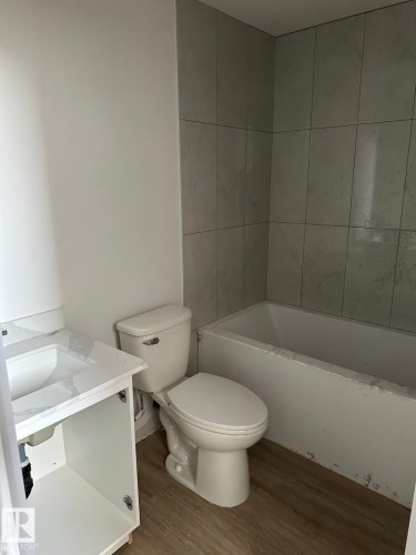 Bathroom featuring a bathtub with tiled surround, a toilet, and a vanity with a sink - 9214 152 Street, Edmonton, AB - Indoor Photo Showing Bathroom