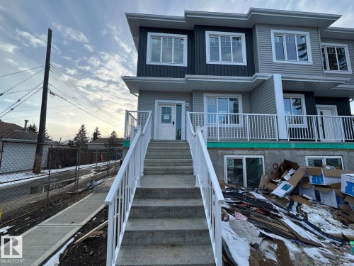 The property features a modern exterior with varied siding, white window frames, and a concrete staircase leading to the entrance - 9214 152 Street, Edmonton, AB - Outdoor With Facade