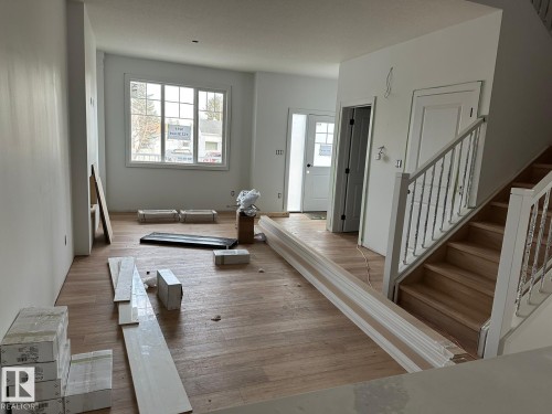 This room features light wood flooring, a window offering natural light, and a staircase with light wood steps and a white railing - 9214 152 Street, Edmonton, AB - Indoor Photo Showing Other Room