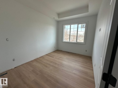 This room features light-toned wood flooring, a window providing natural light, and a tray ceiling detail - 9214 152 Street, Edmonton, AB - Indoor Photo Showing Other Room