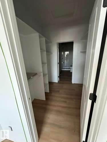 This area features built-in white shelving, light wood-style flooring, and an entryway leading to a bathroom - 9214 152 Street, Edmonton, AB - Indoor Photo Showing Other Room