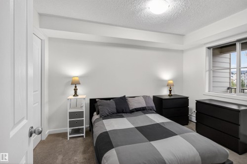 This bedroom features neutral-toned carpeting, white walls, and a window providing natural light - 311 12035 22 Avenue, Edmonton, AB - Indoor Photo Showing Bedroom