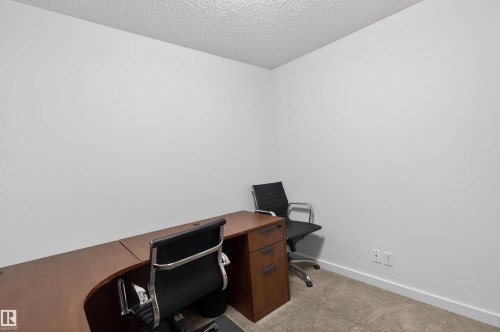 This versatile room features neutral white walls and carpeting, providing a blank canvas for various uses - 311 12035 22 Avenue, Edmonton, AB - Indoor Photo Showing Office