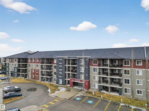The property features a multi-story exterior with a combination of red, grey, and stone facade elements - 311 12035 22 Avenue, Edmonton, AB - Outdoor With Balcony