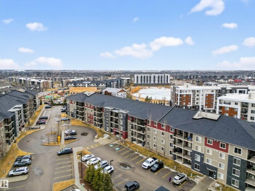 Aerial view showcasing the property's exterior, which features a multi-story building with balconies and a parking lot - 311 12035 22 Avenue, Edmonton, AB - Outdoor With View