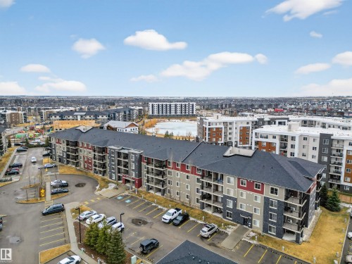 The property features a multi-story building with a dark gray roof and a facade combining red, light gray, and dark gray sections - 311 12035 22 Avenue, Edmonton, AB - Outdoor With View