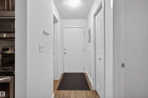 Entryway featuring hardwood-style flooring, a white door, and light-colored walls - 311 12035 22 Avenue, Edmonton, AB - Indoor Photo Showing Other Room