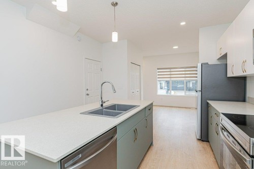 The kitchen features a double sink with a stainless steel faucet, light countertops, and light-colored cabinetry with gold-toned hardware - 9652 Colak Link Link, Edmonton, AB - Indoor Photo Showing Kitchen With Double Sink