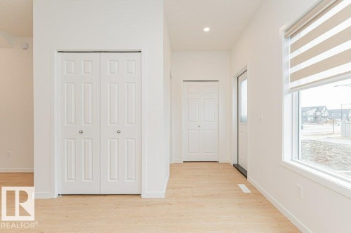 Bright interior featuring light wood flooring, white walls, and a window with horizontal blinds - 9652 Colak Link Link, Edmonton, AB - Indoor Photo Showing Other Room