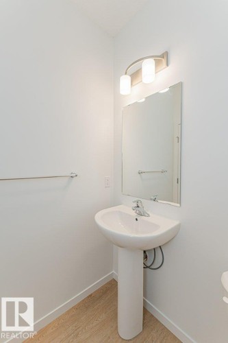 Bathroom featuring a white pedestal sink, a wall-mounted mirror, and a modern light fixture - 9652 Colak Link Link, Edmonton, AB - Indoor Photo Showing Bathroom