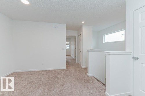 This bright interior space features light-colored carpeting, white walls, and recessed lighting - 9652 Colak Link Link, Edmonton, AB - Indoor Photo Showing Other Room
