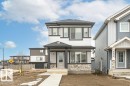 This property features a contemporary exterior with white siding, dark trim, and a stone accent facade - 9652 Colak Link Link, Edmonton, AB  - Outdoor With Facade 