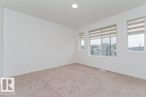 This room features expansive white walls, a light beige carpet, and several windows fitted with blinds - 9652 Colak Link Link, Edmonton, AB - Indoor Photo Showing Other Room