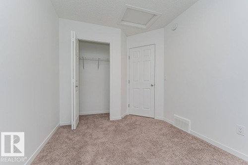 This room features neutral-toned carpet flooring, white walls, and a white paneled door - 9652 Colak Link Link, Edmonton, AB - Indoor Photo Showing Other Room