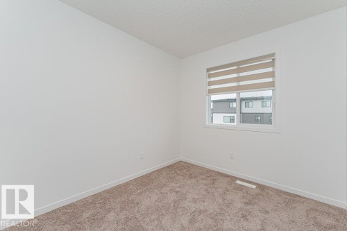This room features a window with blinds, light-colored walls, and carpeted flooring - 9652 Colak Link Link, Edmonton, AB - Indoor Photo Showing Other Room