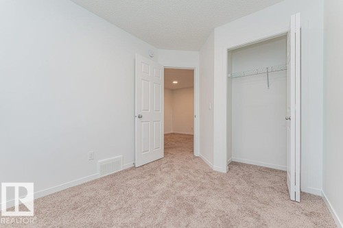 The room features light-colored walls, carpeted floors, and a closet with a wire shelf and hanging rod - 9652 Colak Link Link, Edmonton, AB - Indoor Photo Showing Other Room