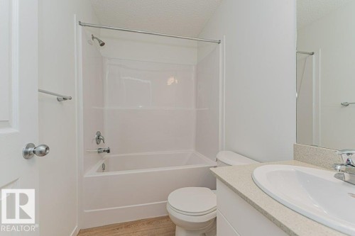 Bathroom featuring a white bathtub and shower combination with a bright white surround, a toilet, and a vanity with a white sink and light-colored countertop - 9652 Colak Link Link, Edmonton, AB - Indoor Photo Showing Bathroom
