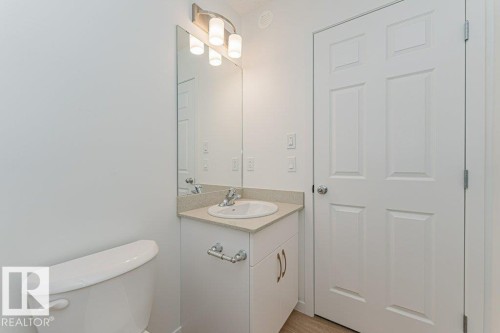 The bathroom features a toilet, a vanity with a countertop and sink, a mirror, and a light fixture - 9652 Colak Link Link, Edmonton, AB - Indoor Photo Showing Bathroom