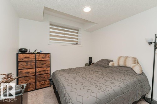 This room features white painted walls, a textured ceiling, and a window with blinds - 9652 Colak Link Link, Edmonton, AB - Indoor Photo Showing Bedroom