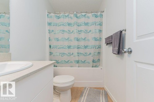 Bathroom featuring a white toilet, a bathtub with a shower curtain, a vanity with a white countertop, and a mirror - 9652 Colak Link Link, Edmonton, AB - Indoor Photo Showing Bathroom
