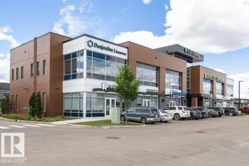 The property features a modern commercial building with a brown and white facade, expansive windows, and a paved parking lot - 9652 Colak Link Link, Edmonton, AB - Outdoor