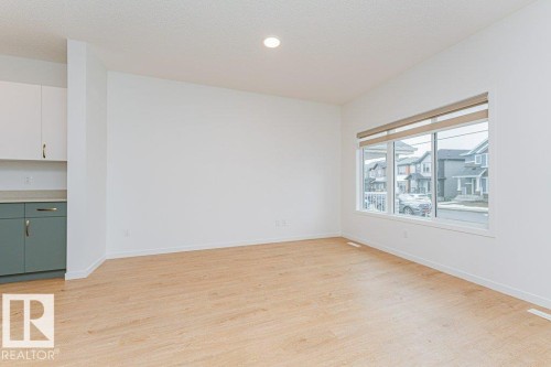 The property features light-toned flooring, white walls, and a large window with blinds - 9652 Colak Link Link, Edmonton, AB - Indoor Photo Showing Other Room