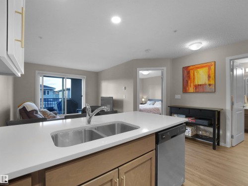 Well-appointed kitchen featuring a stainless steel double basin sink, light-colored countertops, and integrated dishwasher - 214 394 Windermere Road, Edmonton, AB - Indoor Photo Showing Kitchen With Double Sink