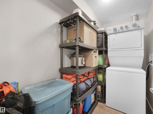 The property features a laundry area with a stacked washer and dryer, providing practical utility - 214 394 Windermere Road, Edmonton, AB - Indoor Photo Showing Laundry Room