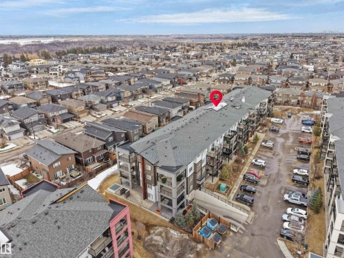 Aerial view showcasing the property's exterior, including a large parking area and numerous balconies - 214 394 Windermere Road, Edmonton, AB - Outdoor With View
