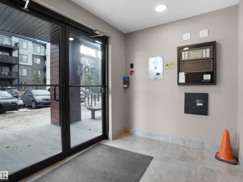 The property features a well-maintained entrance with glass doors, a grey floor mat, and neutral-toned walls - 214 394 Windermere Road, Edmonton, AB - Indoor Photo Showing Other Room