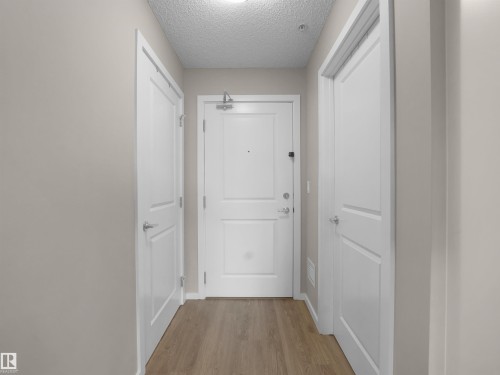 Entryway with light wood-style flooring, white panel doors, and neutral wall paint - 214 394 Windermere Road, Edmonton, AB - Indoor Photo Showing Other Room