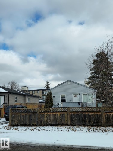 The property features light blue siding, a white front door, and a wooden fence along the front - 10541 157 Street, Edmonton, AB - Outdoor