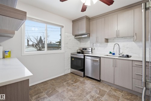 The kitchen features light-toned cabinetry, stainless steel appliances, a white countertop, and a tiled backsplash - 16049 95 Avenue, Edmonton, AB - Indoor Photo Showing Kitchen