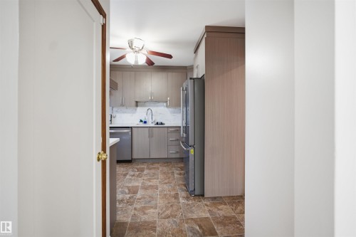 The kitchen features light-colored cabinetry, a stainless steel refrigerator, and a ceiling fan with integrated lighting - 16049 95 Avenue, Edmonton, AB - Indoor Photo Showing Other Room