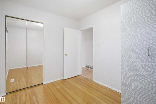 This room features hardwood flooring, white walls, and a white door with a brass-toned doorknob - 16049 95 Avenue, Edmonton, AB - Indoor Photo Showing Other Room