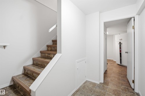 This property features a staircase with tiled steps and a white handrail, along with a hallway showcasing tiled flooring and white walls - 16049 95 Avenue, Edmonton, AB - Indoor Photo Showing Other Room