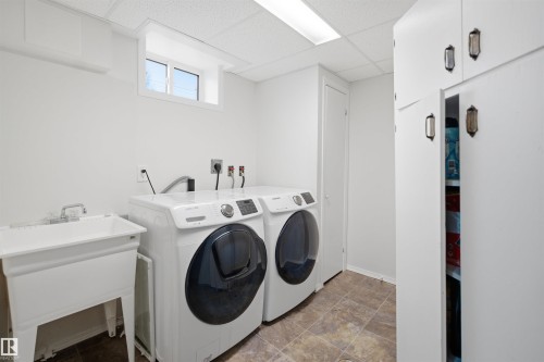This laundry area features a utility sink, a window providing natural light, and cabinetry for storage - 16049 95 Avenue, Edmonton, AB - Indoor Photo Showing Laundry Room