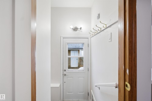 Entryway featuring a white door with a window, a wall-mounted light fixture, and a row of coat hooks - 16049 95 Avenue, Edmonton, AB - Indoor Photo Showing Other Room
