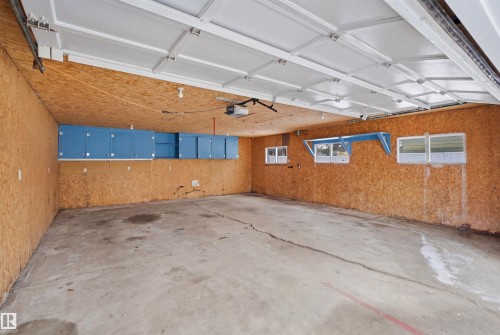 Spacious garage featuring a concrete floor, light wood paneled walls, and blue storage cabinets - 16049 95 Avenue, Edmonton, AB - Indoor Photo Showing Garage