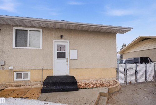 The property features an exterior with light-colored stucco and a white door with a window - 16049 95 Avenue, Edmonton, AB - Outdoor With Exterior